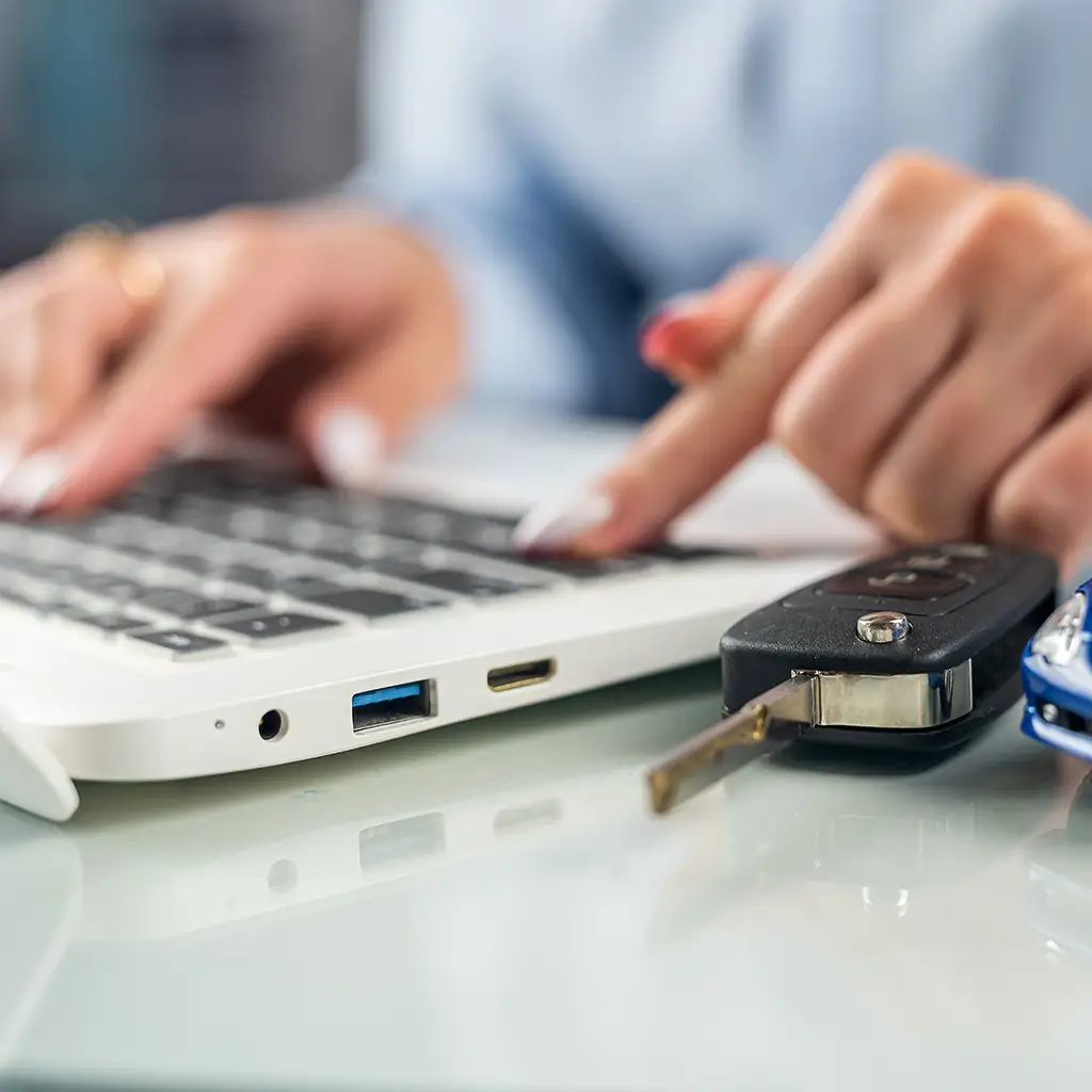 Frau und Autoschlüssel vor Laptop