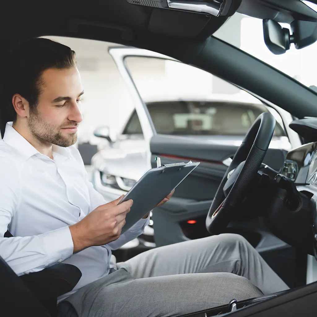 Mann ließt Unterlagen im Auto